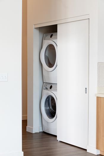 A white door is open to reveal a white washing machine.